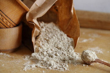 Hazelnut flour in a wooden spoon on a wooden table.