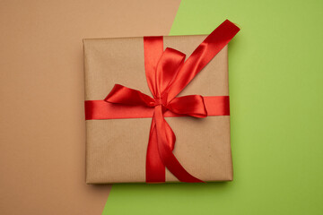 box wrapped in brown paper and tied with a silk red ribbon with a bow