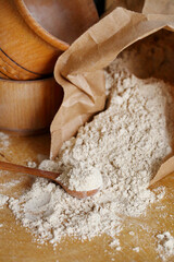 Hazelnut flour in a wooden spoon on a wooden table.