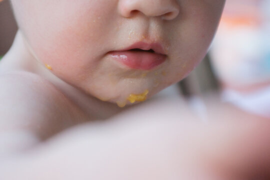 Lower half of baby's face with remnants of fruit stuck to skin