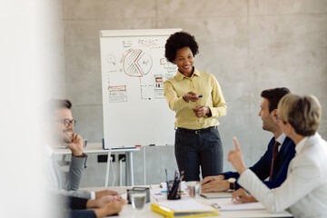 Obraz premium Happy African American businesswoman answering a colleague's question during a presentation.