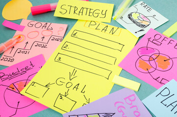 Closeup of colorful paper notes on the blue table.Handwritten notes for Plan, Offer, Goals, Strategy