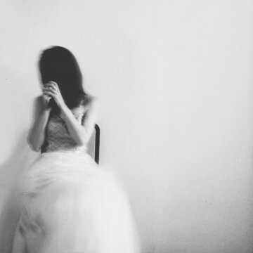 Woman wearing an evening gown, holding her hair in front of her face - intentionally blurred