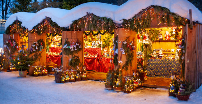 Romantic Christmas market with illuminated shops in wooden huts with gifts and handmade decoration.