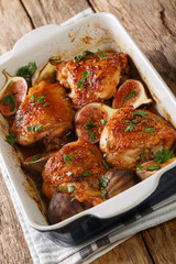 Delicious baked balsamic chicken thighs with figs and herbs close-up in a baking dish. vertical