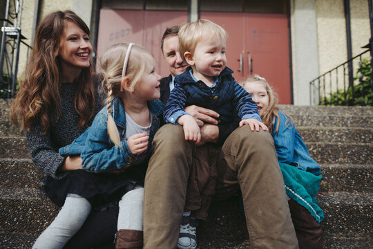 Young family of five enjoying time sitting outside on steps