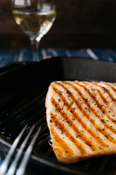Salmon fillet in a griddle and a glass of white wine