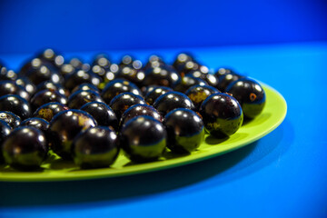 Jaboticaba (Myrciaria cauliflora) fruits in green dish on blue background