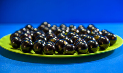 Jaboticaba (Myrciaria cauliflora) fruits in green dish on blue background