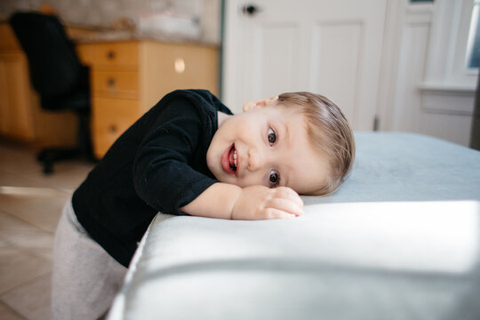 Cute toddler boy leaning his head on an ottoman