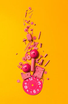 Disassembled pink clock on orange background.