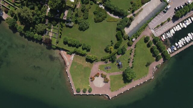 Il sole di Ranco restaurant and Lake Maggiore lakeside resort with green manicured landscape, red terracotta roofs, boat dock and pool, Italy, directly above aerial approach