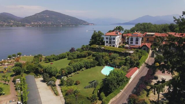Aerial flight towards Lake Maggiore above green Italian garden and vacation home