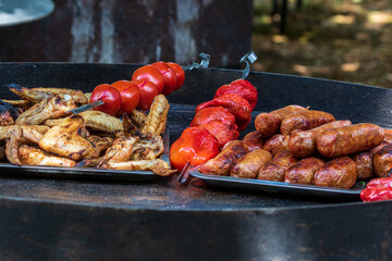 Healthy street food to go - sausages, poultry, meat, bell peppers and red tomatoes. Delicious food cooked over an open fire, which is offered at a street food fair, event, festival.
