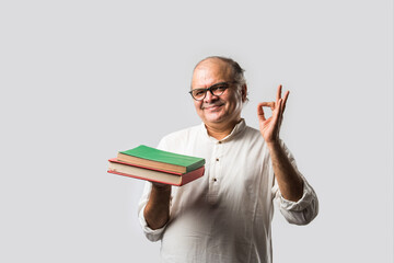 Indian retired senior or old man reading book or newspaper