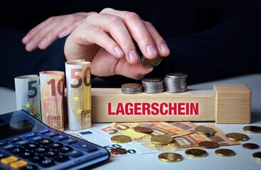 Lagerschein. Hand baut Geldstapel auf einem Baustein mit Text. Turm aus Euro Münzen....