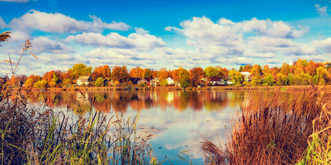 Autumn landscape with lakeside houses and clouds