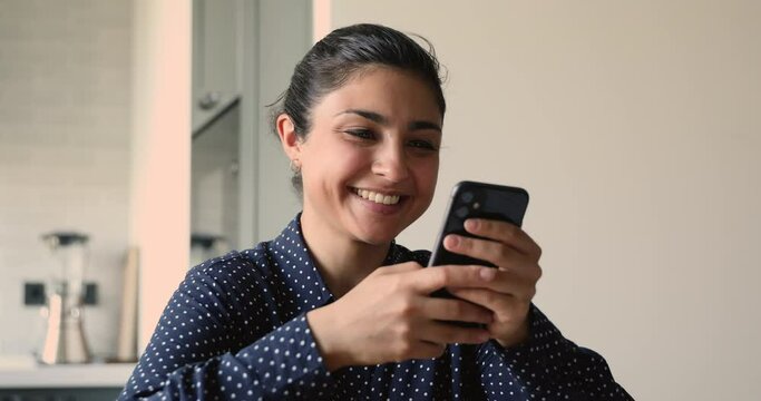 Indian female holds cellphone laugh over sms from boyfriend, enjoy online chat with friends in social media networks, watch funny videos, spend free time using modern tech internet connection concept