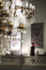 a photo in focus of a wife and a husband in a Muslim temple vertically