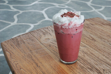Close up of iced red velvet latte on top of a wooden table.