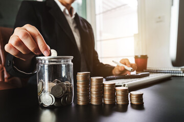 businessman holding coins putting in glass with using smartphone and calculator to calculate  concept saving money