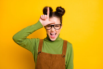Photo of crazy youngster lady two buns bad person student grimacing showing loser symbol forehead...