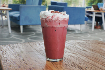 Close up of iced red velvet latte on top of a wooden table.