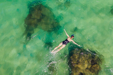 The woman is snorkeling among the corals. View from the drone
