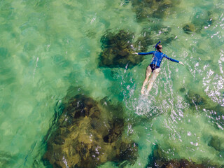 The woman is snorkeling among the corals. View from the drone