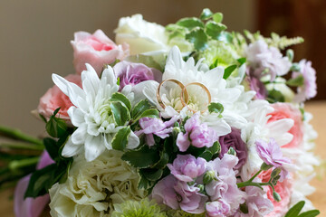 Wedding rings lie on the petals of a flower bridal bouquet,