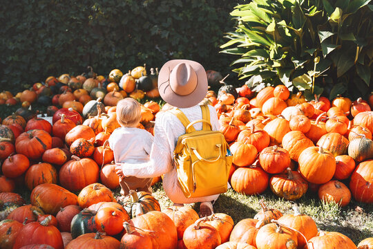 Mother and child at pumpkin patch outdoors.