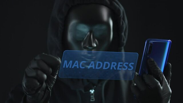 Hacker wearing black mask pulls MAC ADDRESS tab from a smartphone. Hacking concept