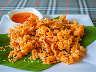 Crispy fried shrimp on a banana leaf on a white plate