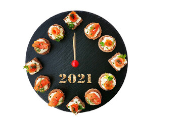 Happy New Year 2021! Smoked salmon canapes on black slate platter form a clock face showing midnight isolated