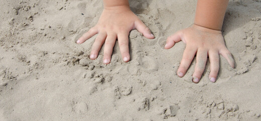 children's hands on the sand selective focus