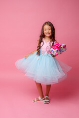 a little girl of Asian appearance holds a gift in her hands celebrating her birthday on a pink background