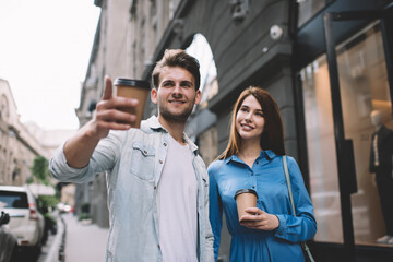 Loving couple with to go beverage sightseeing while walking along street in downtown