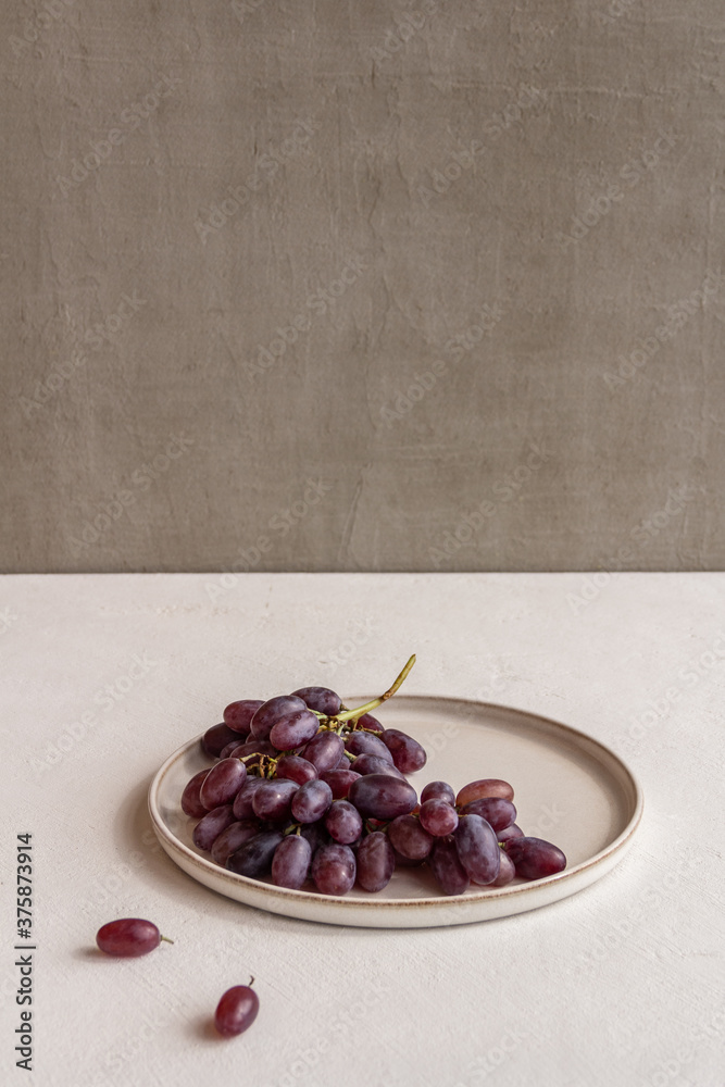 Wall mural fresh juicy grapes on a plate on a light background