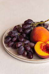 juicy fresh peaches and grapes on a plate on a light background
