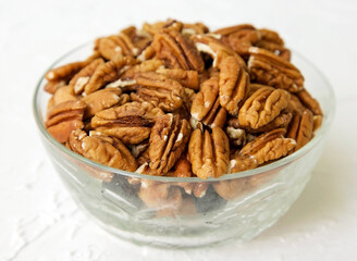 Dried pecan in a glass cup on a white textured background