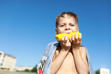 Child eating boiled corn on beach
