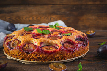 Delicious homemade plum pie on rustic background
