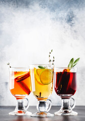 Mulled wine from red and white wine and hot mulled cider. Autumn or winter drinks and cocktails in glass mugs with spices and citrus fruit