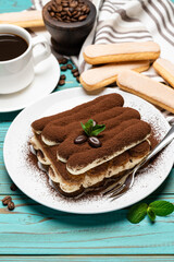portion of Classic tiramisu dessert, cup of coffee and savoiardi cookies on wooden background