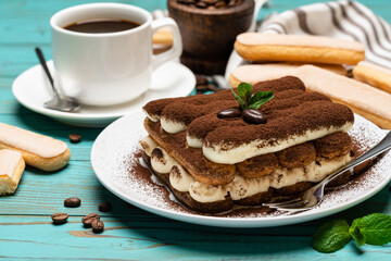 portion of Classic tiramisu dessert, cup of coffee and savoiardi cookies on wooden background