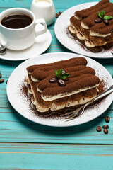 Two portions of Classic tiramisu dessert, cup of coffee and milk or cream on colorful blue wooden background
