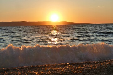 Beautiful orange sunset with waves on th beach