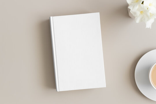 White Book Mockup With A Cup Of Coffee And Oleander On A Beige Table.