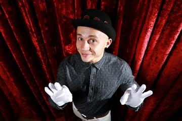 Young caucasian man in black bowler hat  with funny face and white gloves posing like master of...