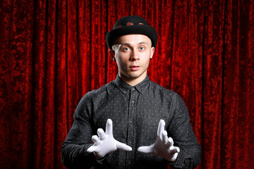 Young caucasian man in black bowler hat  with funny face and white gloves posing like master of...
